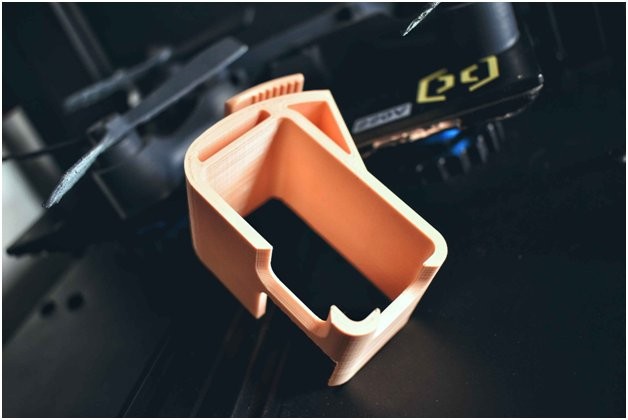 A orange model is printed on the Artillery Genius 3D printer
