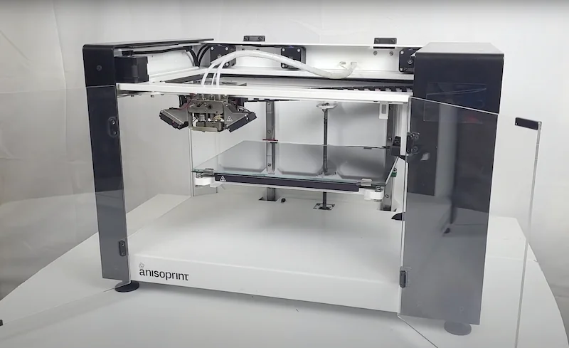 Anisoprint Composer A4 3D printer in studio setting; features dual extrusion system, transparent casing; creates composite parts.