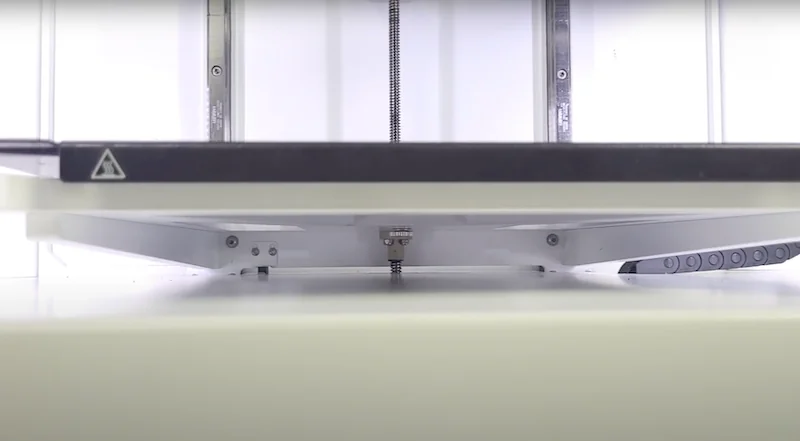 Anisoprint Composer A4 3D printer close-up, focusing on the build platform and mechanics, showcasing part creation capabilities.