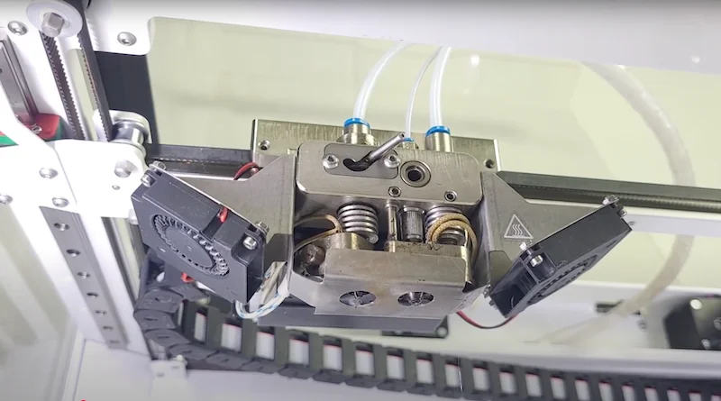 Anisoprint Composer A4 printhead, detailed metal components and dual fans, in a clear 3D printing enclosure.