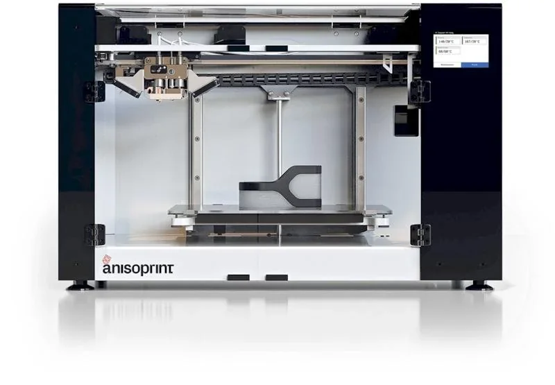 Anisoprint Composer A4 3D printer showing a printed carbon-fiber composite part inside, featuring a sleek black and white design with branding.