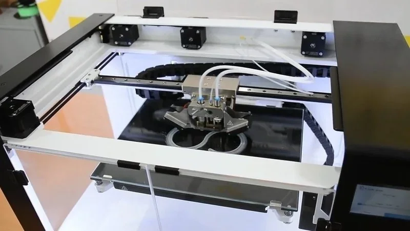 Anisoprint Composer A4 3D printer, open-frame design, printing dual circle parts, showcasing precision and advanced filament feeding system.