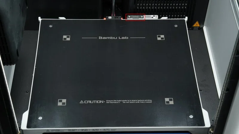 Bambu Lab printer platform, smooth black surface with branding and caution text, designed for precision 3D printing with Bambu H2D technology.
