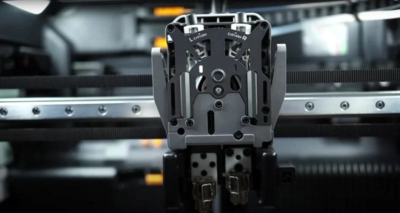 Bambu H2D 3D printer extruder assembly in a sleek, metallic design, showcasing dual extruders for precise, high-detail printing in a modern setting.