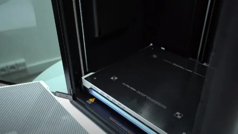 Bambu Lab H2D Pro 3D printer interior with branding visible, showcasing a large build plate designed for printing parts, situated in a workshop setting.