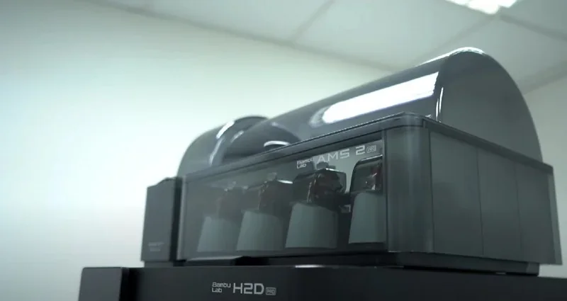 Bambu Lab H2D Pro 3D printer with AMS 2 system in a modern, well-lit room, highlighting advanced filament management and sleek design.