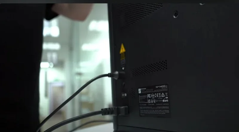 Bambu Lab H2D Pro rear view showing power and data cables connected, office setting, visible labels, no samples or parts shown.