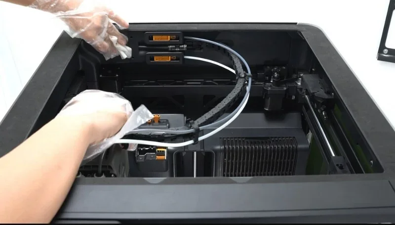 Hands adjusting the filament system inside a Bambu Lab H2D Pro 3D printer, showing printer's internal mechanics and components.
