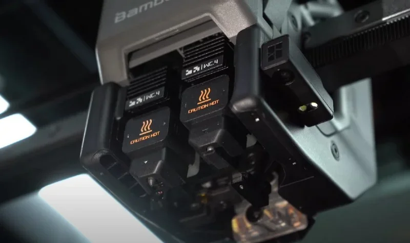 Bambu Lab H2D Pro 3D printer close-up, focusing on heated components labeled "Caution Hot," showcasing advanced design elements.