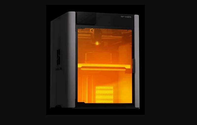 Bambu Lab H2S 3D printer with orange-lit chamber; sleek design and partial view of printed part inside, showcasing precision technology.