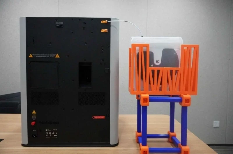 Bambu Lab H2S 3D printer on a table with colorful filament holder.