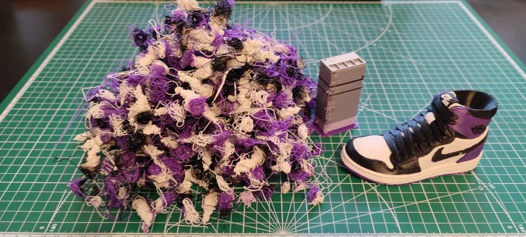 Bambu Lab X1 creations: tangled filament ball, gray model tower, and a mini shoe model on a cutting mat.