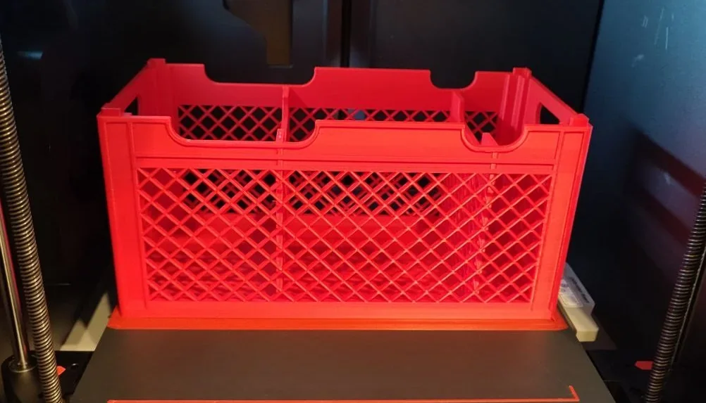 Red 3D-printed crate with lattice design created by Bambu Lab X1, inside the printer.
