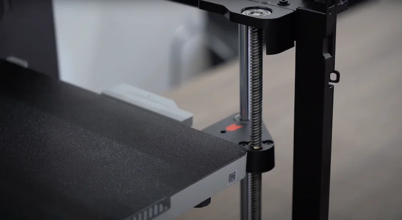 Bambu P1P 3D printer's build platform and vertical screw in a workshop setting.