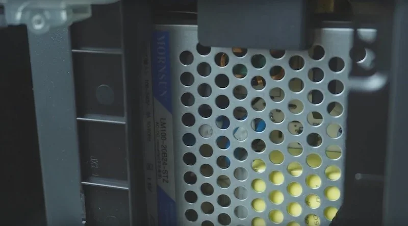 Bambu P1P 3D printer's internal view showing perforated metal component and visible brand, likely showcasing its intricate manufacturing parts.