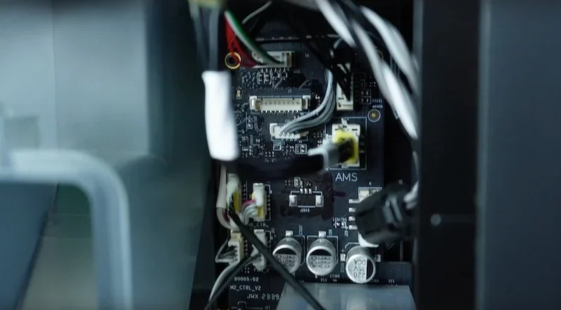 Bambu P1P 3D printer internal wiring, showing circuit board with capacitors and connectors.