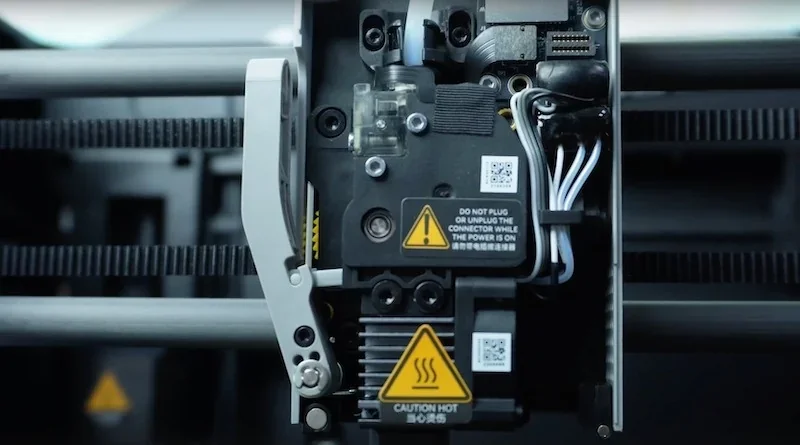 Bambu P1P 3D printer's extruder and wiring close-up, featuring caution labels and detailed mechanical components.