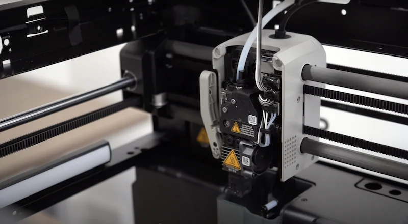 Bambu P1P 3D printer close-up showing nozzle and inner mechanics with branding visible.