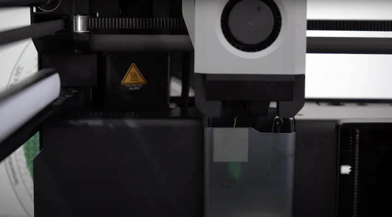 Bambu P1P 3D printer close-up, showcasing the extruder mechanism with visible branding, and sample parts being created in action.