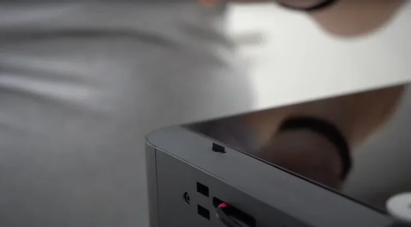 Close-up of the Bambu P1S 3D printer showing sleek edges and buttons, with reflection detail on the surface, in a modern environment.