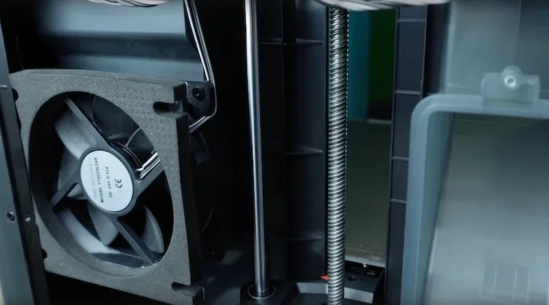 Bambu P1S 3D printer interior showing cooling fan, metal rods, and mechanical components for precision printing.