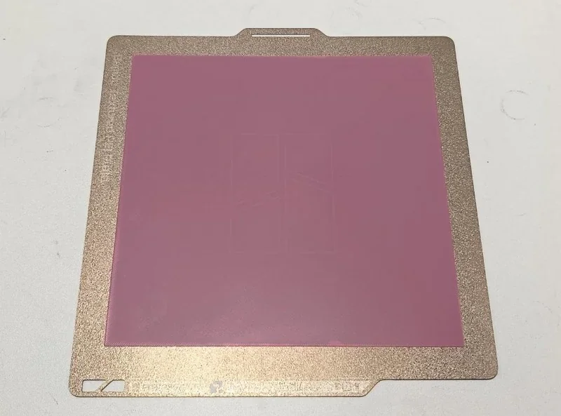 Bambu P2S 3D printer's print bed, featuring a textured gold border and a pink central area, suitable for producing precision parts and samples.
