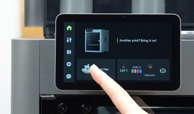 Touchscreen of Bambu P2S 3D printer displaying print options and status, with a finger selecting a function.