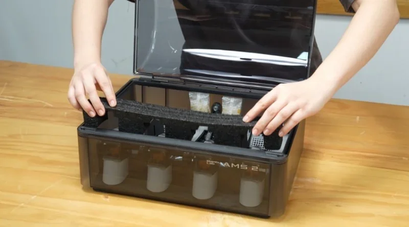 Bambu P2S 3D printer's open lid showing internal components and filter setup on a wooden table, demonstrating assembly or maintenance process.