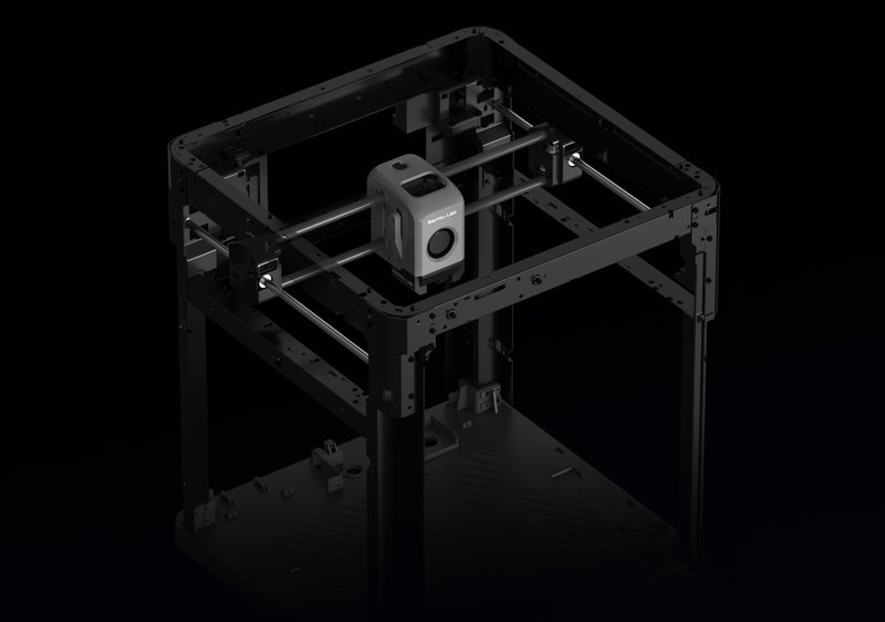 The Bambu Lab X1E 3D printer frame, showcasing its open structural design. The image highlights the printer's metallic frame and gantry, with visible belts and motors for precise movement. Atop the frame is the central extruder assembly, which includes the nozzle and filament feeding system. The setting is a dark background, emphasizing the industrial and robust build of the Bambu X1E, known for high precision and reliability in 3D printing tasks.
