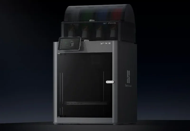 Bambu X1E 3D printer with touchscreen display, sleek black finish, and filament spools visible on top in a dark setting.