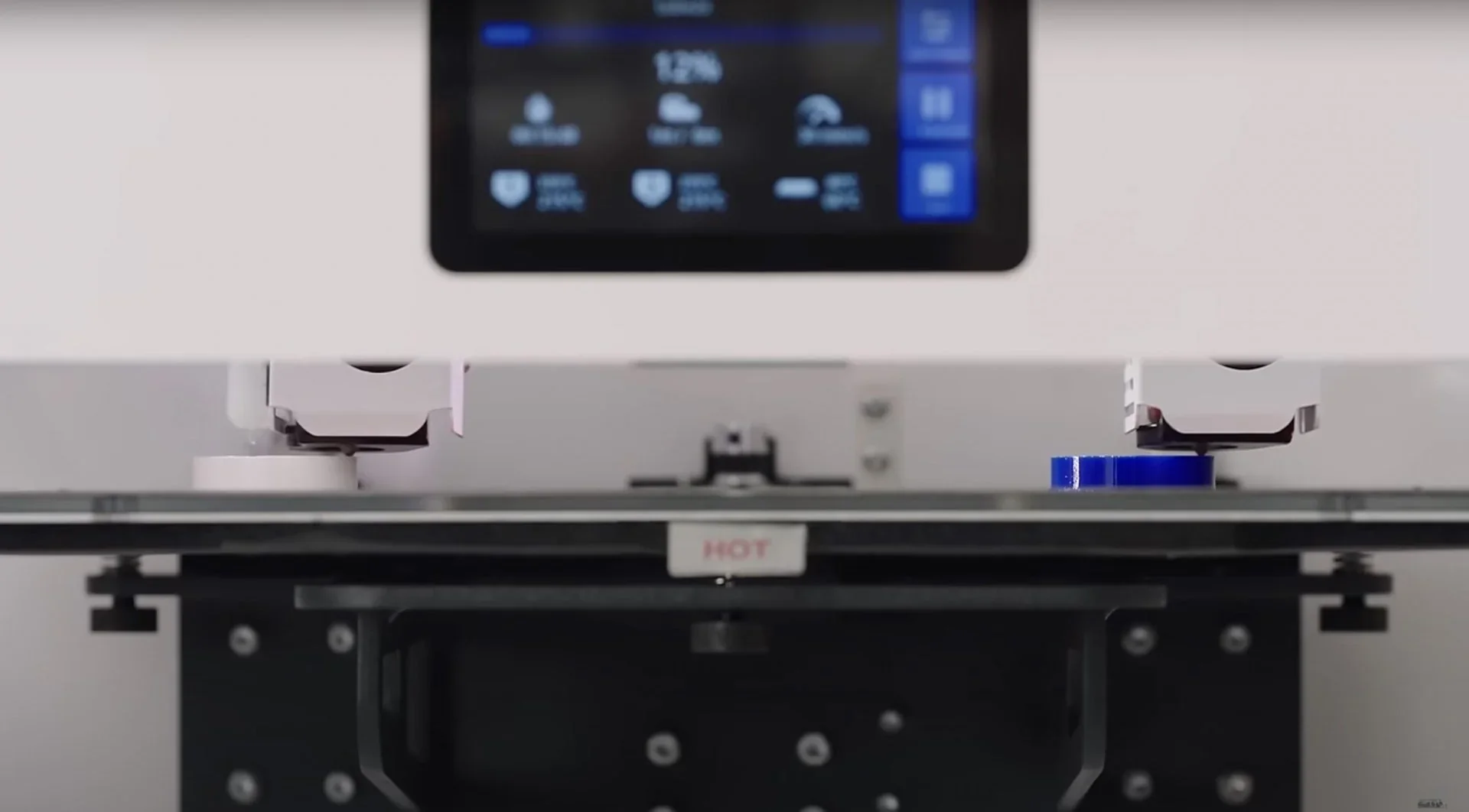 Craftbot Flow IDEX XL with dual extruders working on 3D parts; screen displays progress.