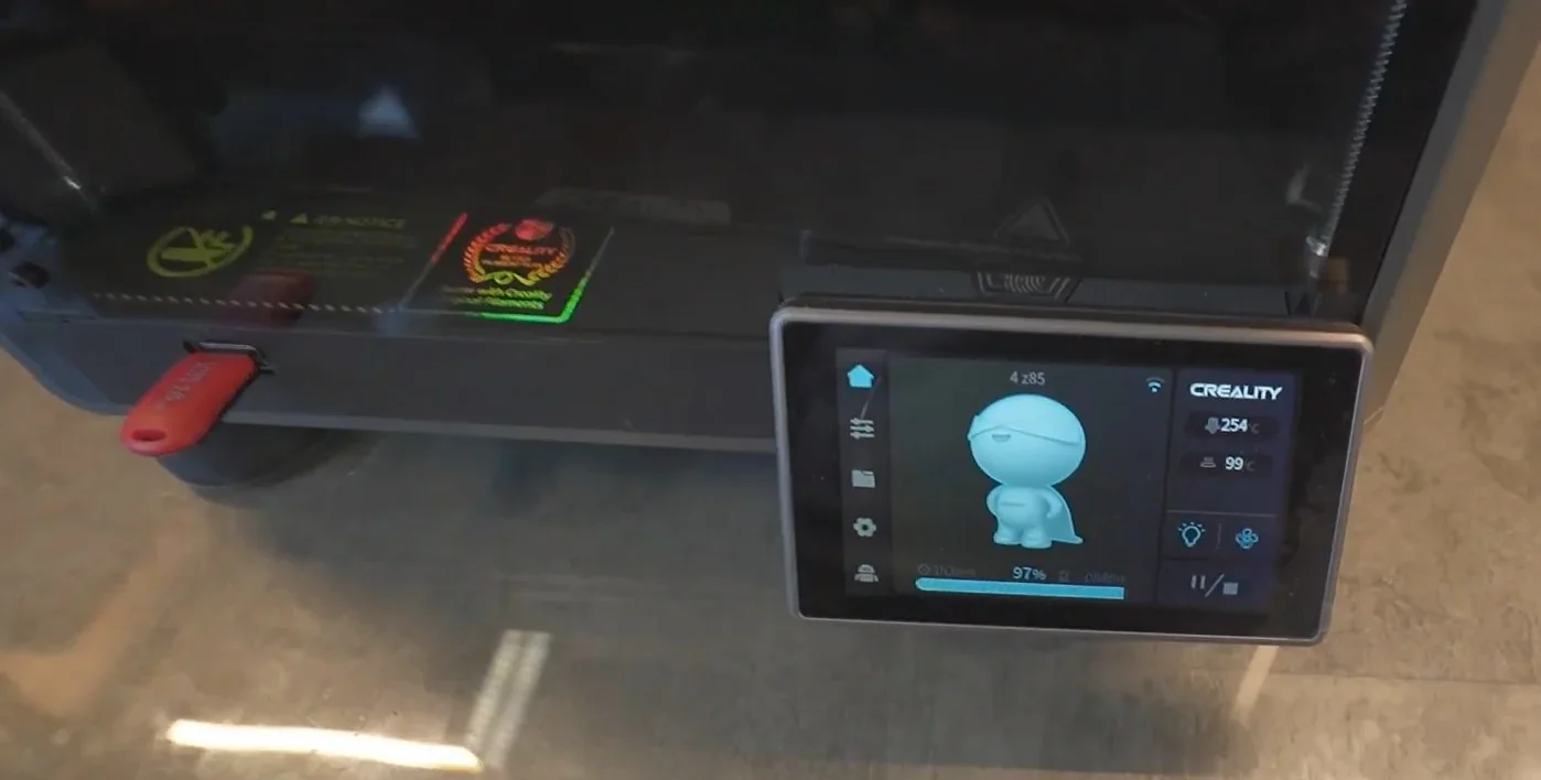 Creality K1 3D printer with touchscreen display showing a print progress at 97%, USB drive inserted, and temperature settings visible.