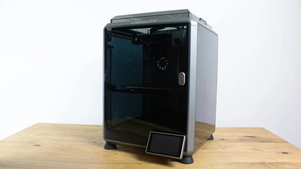 Creality K1 3D printer with sleek design, black enclosure, and Creality branding on a wooden table, suitable for high-precision printing.