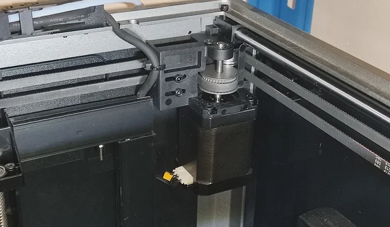 Creality K1 3D printer internal mechanism showcasing motor, gears, and wiring, illustrating precision engineering and build quality.