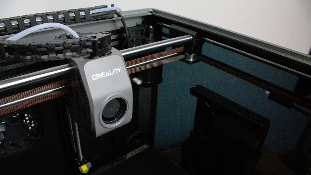 Creality K1 3D printer interior with branding visible, showing extruder and filament guide system in a professional setup.