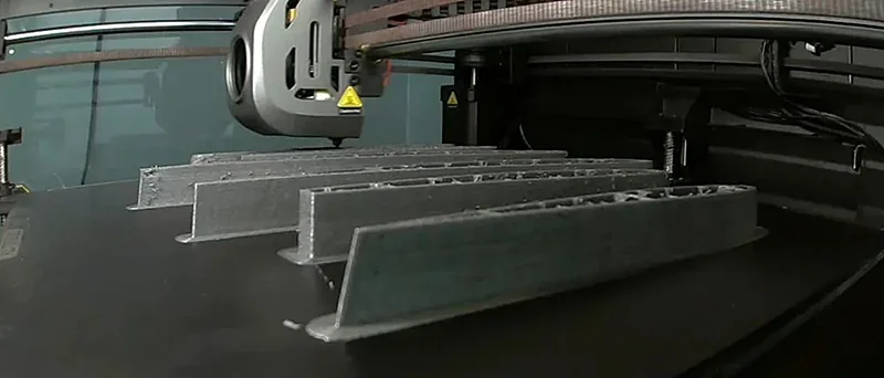 Creality K1 Max 3D printer creating multiple gray structural parts on a flat print bed, showcasing precision and detail in a workshop setting.