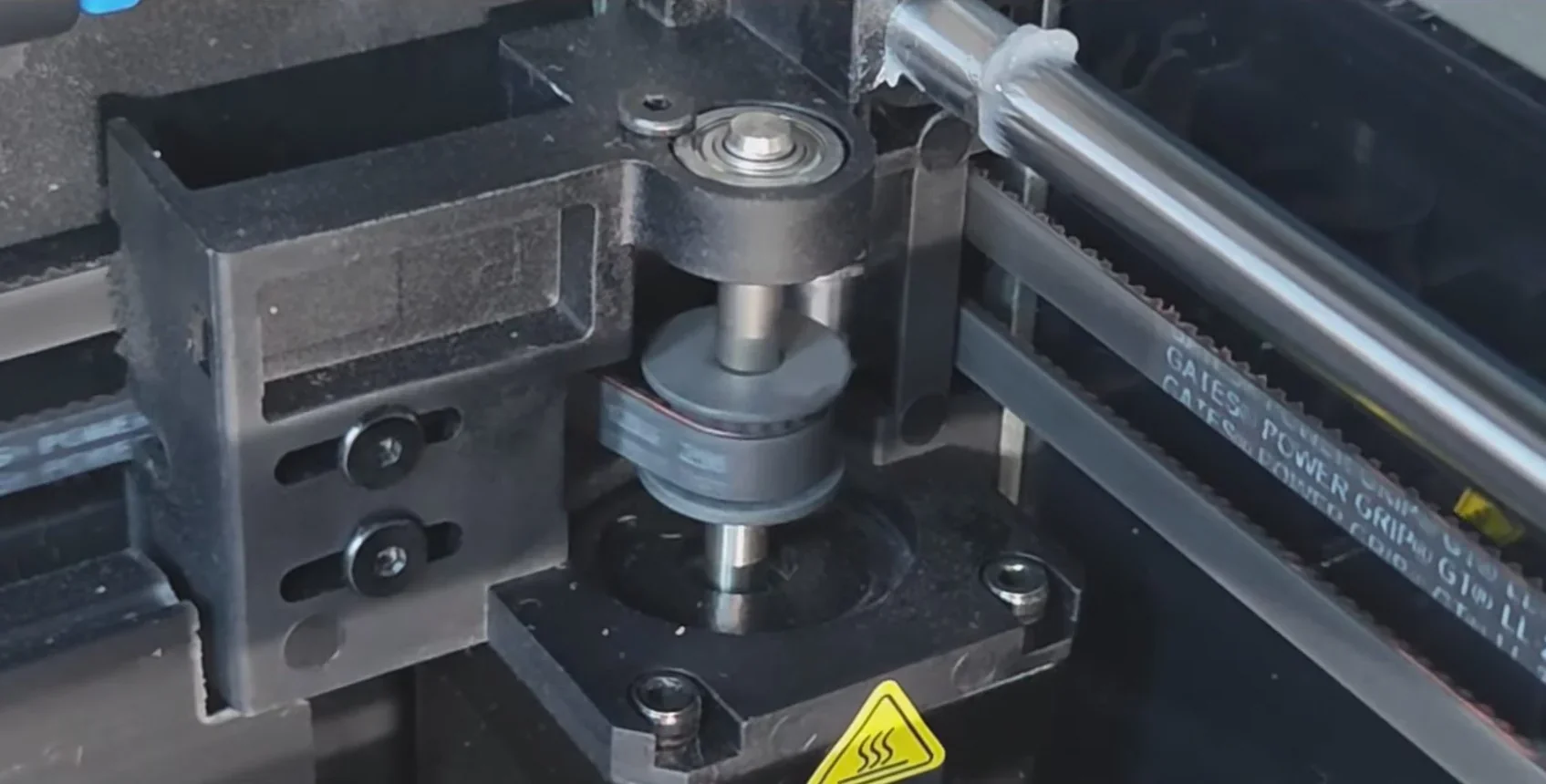 Creality K1 Max 3D printer close-up showing internal pulley mechanism and belt system with visible branding.