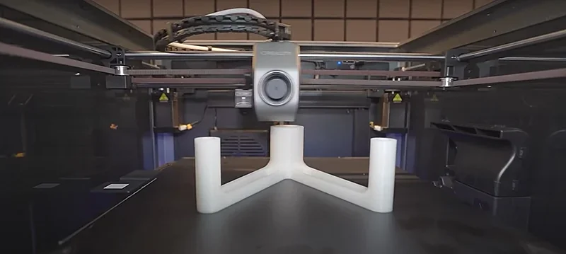 Creality K1 Max 3D printer showcasing a white plastic part being printed, featuring a sleek design and precise build environment.