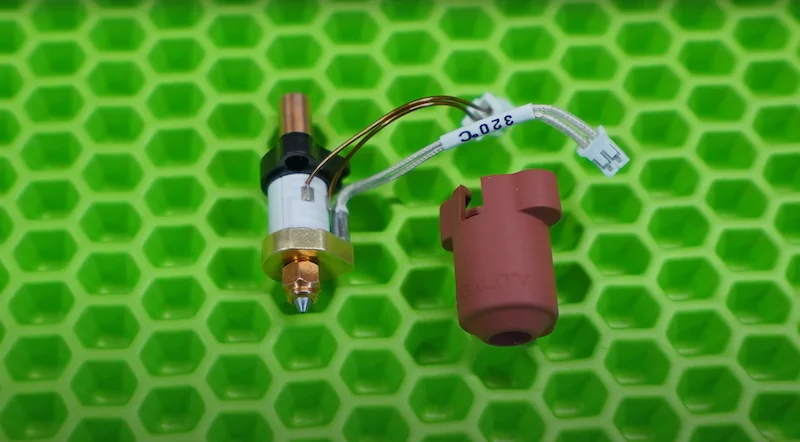 Creality K1 Max 3D printer nozzle and wiring on textured green background.