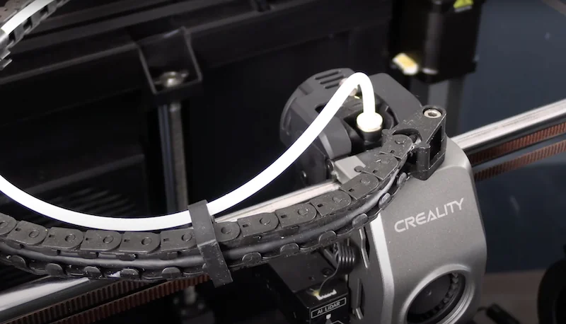 Creality K1 Max 3D printer close-up shows extruder and filament tube, highlighting mechanical components and branding.