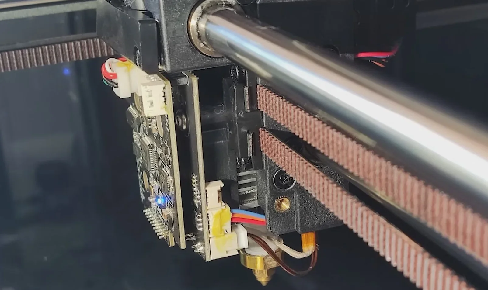 Creality K1 Max 3D printer close-up showing extruder mechanism, circuit board, wires, and guide rails.