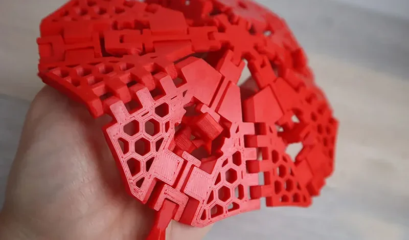Red geometric 3D-printed structure with hexagonal and interlocking patterns, created by the Creality K1 Max.