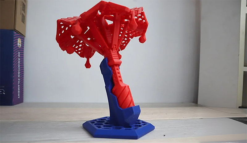 Red and blue intricate 3D printed structure created by Creality K1 Max, showcasing detailed design on a table with plain background.