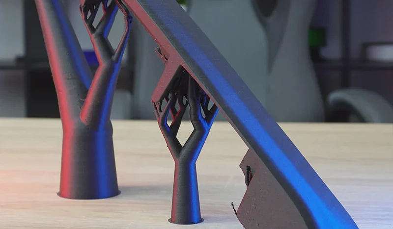 Creality K2 3D-printed tree-like support structures on a wooden table, showcasing precision engineering with blue and red lighting.