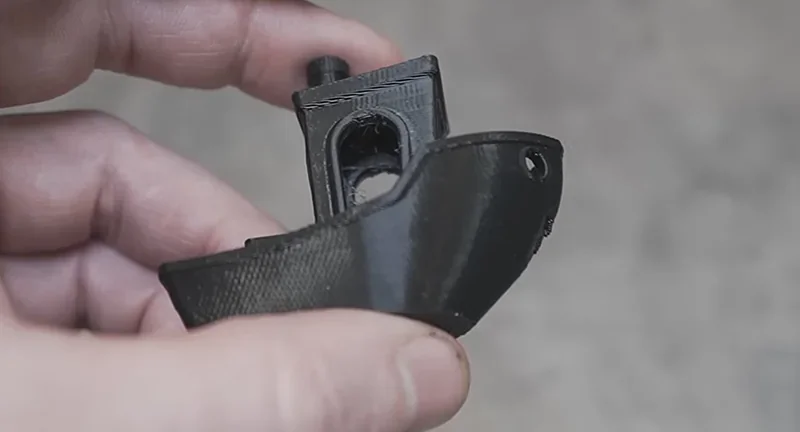 Hand holding a 3D printed small black boat model, created by Creality K2, showcasing print quality and details.