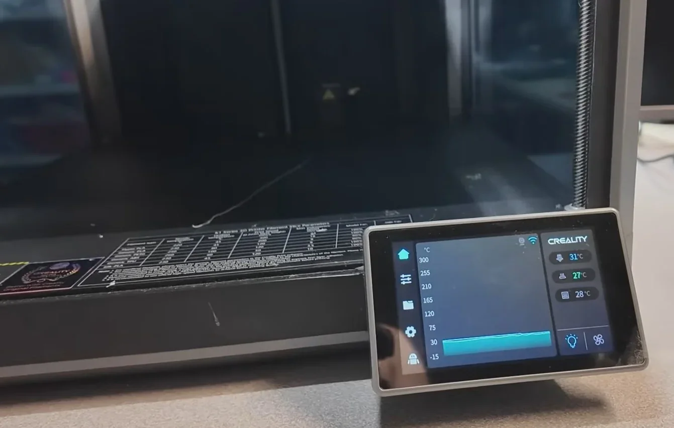 Creality K2 3D printer's control panel displaying temperature settings, with visible branding and printer details printed on a label.