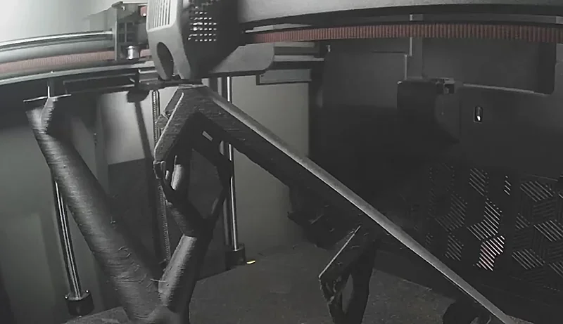 Creality K2 3D printer at work producing intricate black filament object with high precision, showcasing internal printing setup and mechanics.