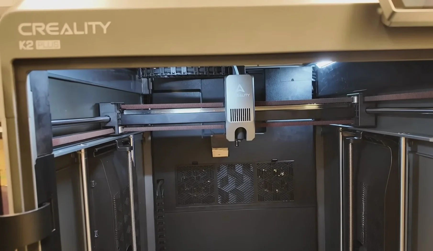Creality K2 Plus 3D printer interior showing print head, rails, and branding, designed for creating precise models and prototypes.