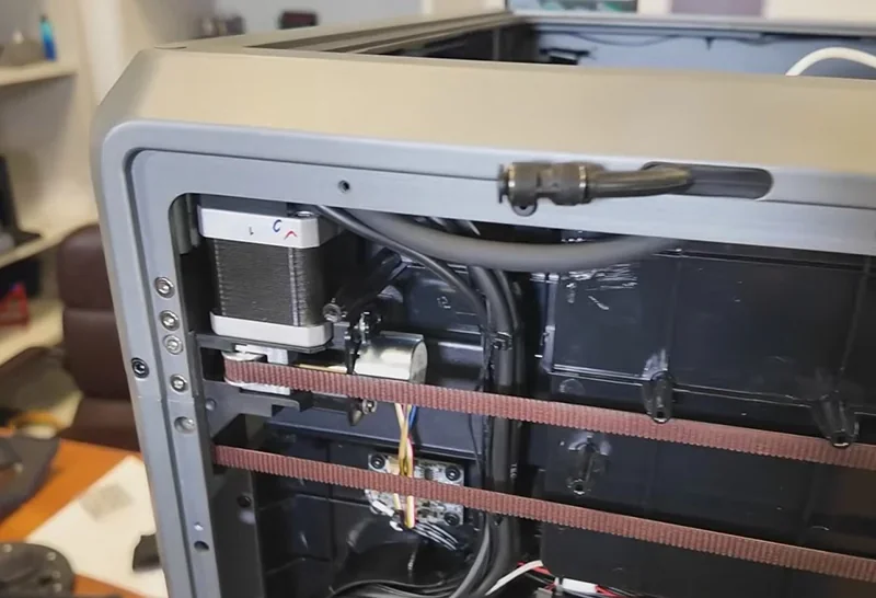 Creality K2 3D printer mechanism showing internal components, motor, belts, and wiring, highlighting its technical assembly and design.