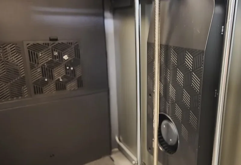 Creality K2 3D printer interior with geometric patterned casing and vertical steel rods, showcasing design and build quality.